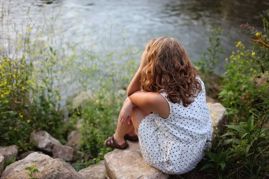 girl sitting on rock by lake