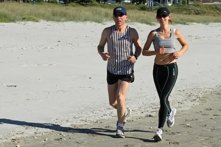 man and woman running on beach