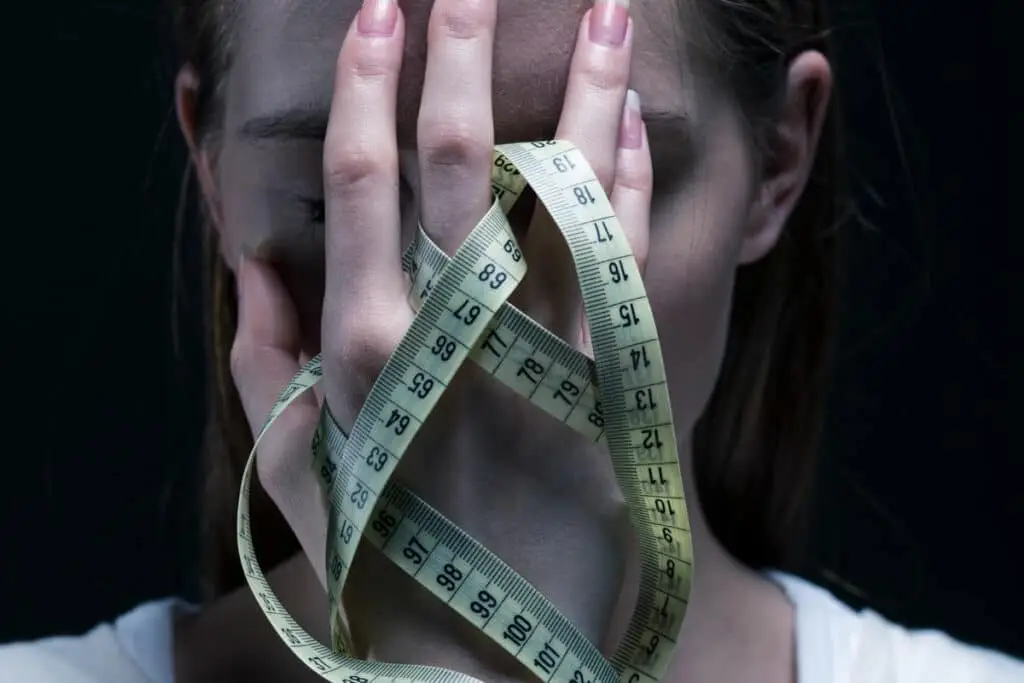 girl holding her face with measuring tape in hand