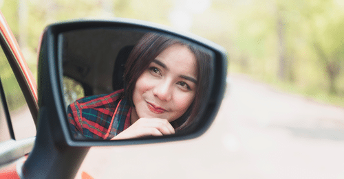 girl leaving troubles behind looking in rear view mirror
