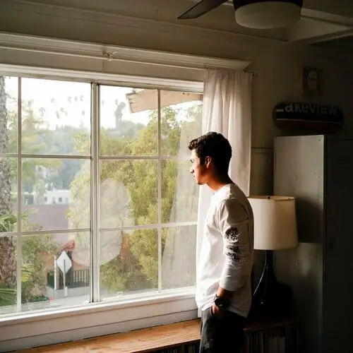 guy standing in window looking bored with cabin fever