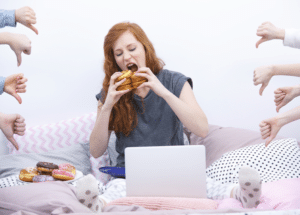 girl eating burger with people giving her multiple thumbs down