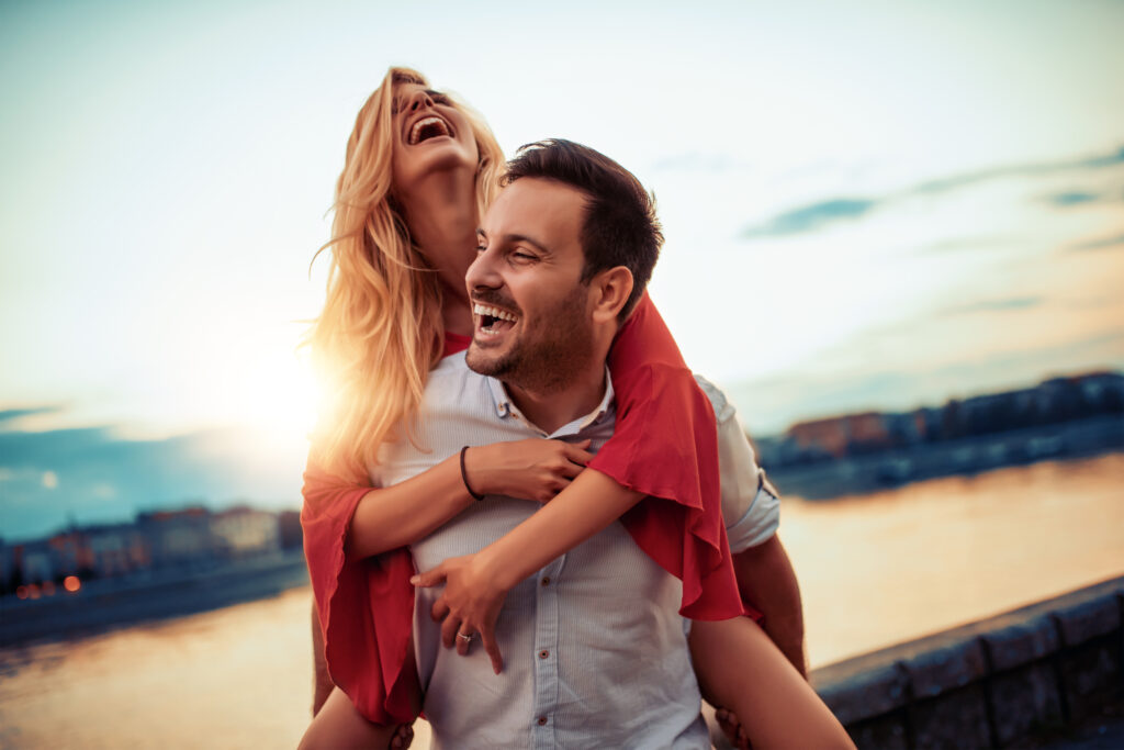 A woman is getting a piggy back ride from her male partner and she is exhibiting signs of the feel good hormone oxytocin.