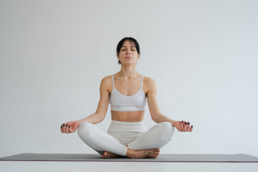 Woman sitting on the floor with her legs crossed, arms on knees, and eyes closed deep in mediation to stimulate her vagus nerve.