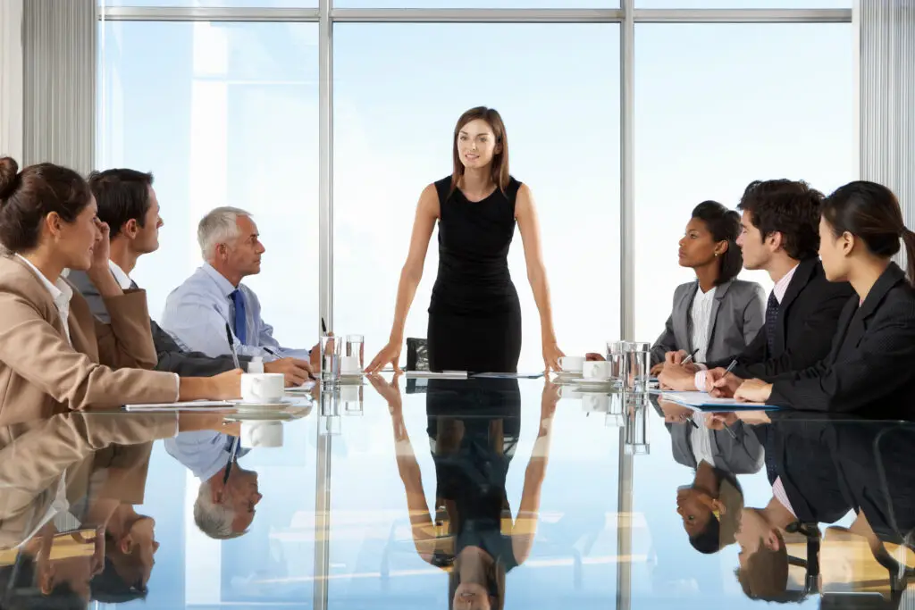 This image shows a woman standing at the head of a table with people on both sides. This represents how executive functioning skills help manage the brain.