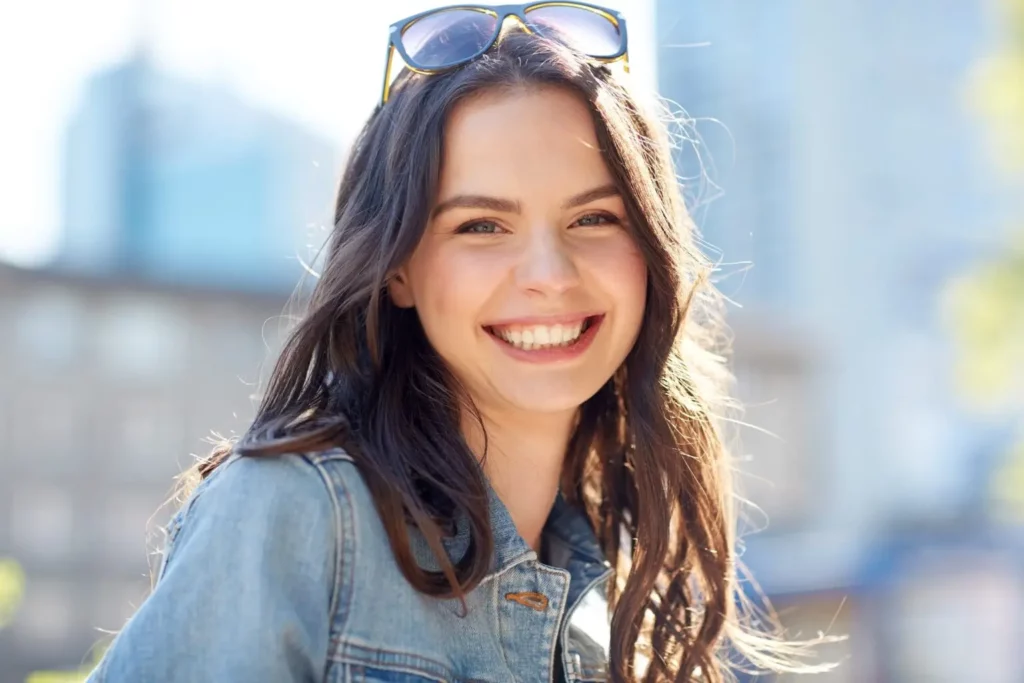 A young woman happy and excited, smiling ear-to-ear because she has an OCD symptom management plan that is working to help her obsessions and compulsions.