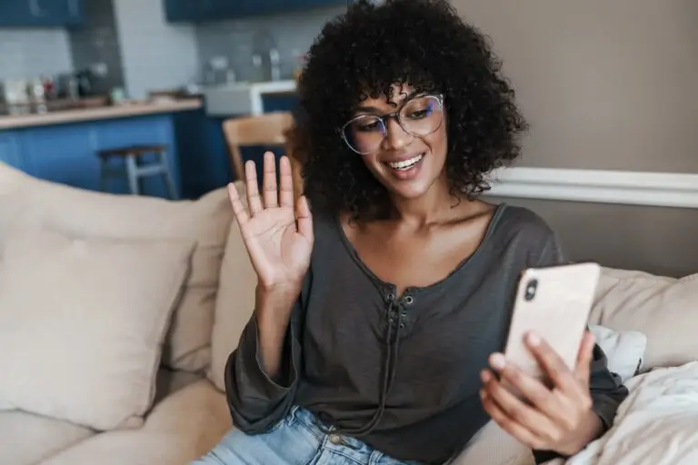 7-question eating disorder test: Is your relationship with food unhealthy? a young, happy, black woman greeting her online therapist with a wave to the camera.