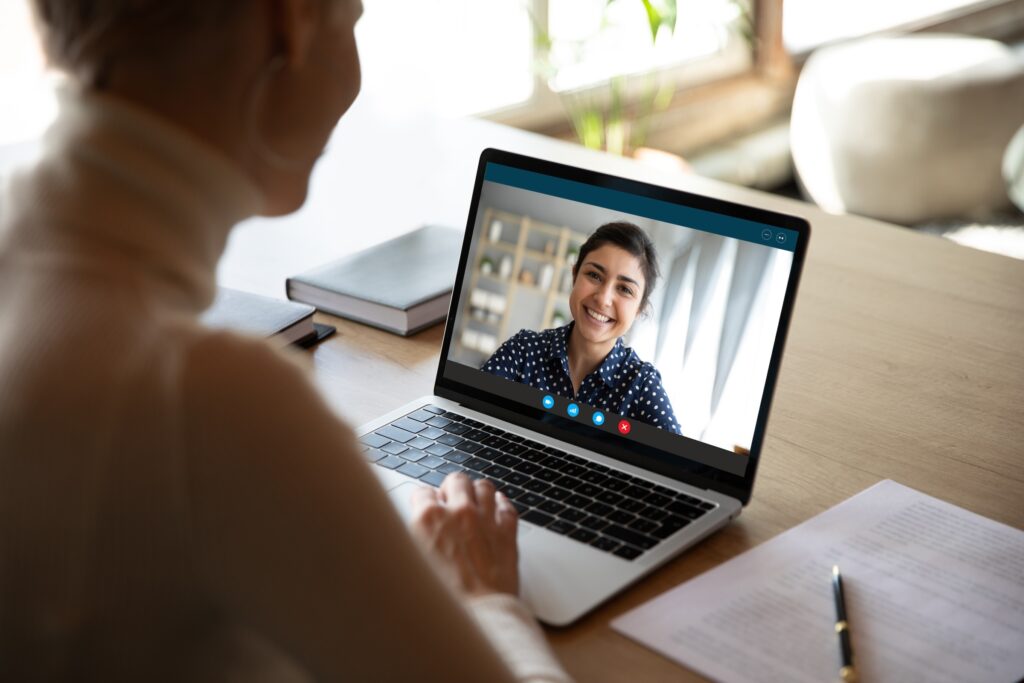 7-question eating disorder test: Is your relationship with food unhealthy? A sophisticated woman in a turtle neck and hair pinned up having a video session with her online therapist for her eating disorder.