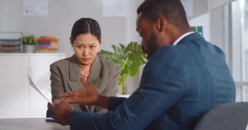 A young asian woman lacking confidence to confront her boss while he talks down to her.