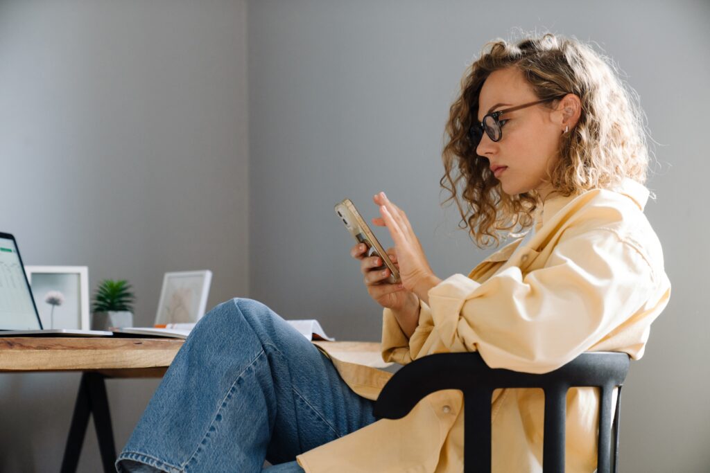 7-question eating disorder test: Is your relationship with food unhealthy? A young curly haired woman sitting in her desk chair, legs crossed, while she takes an online eating disorder test.