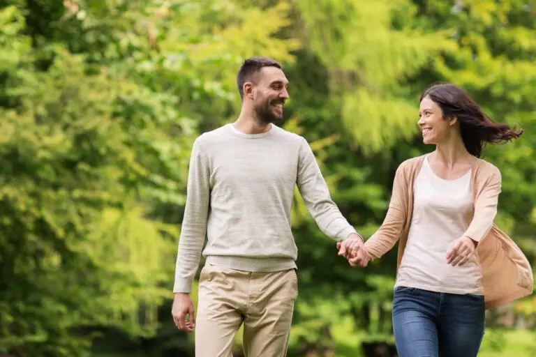 How to overcome codependency in time to save your relationship a young couple walking outside, holding hands, smiling as they walk.