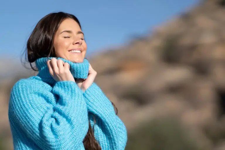 woman standing outside in the fresher, smiling with her eyes closed as the sun hits her face