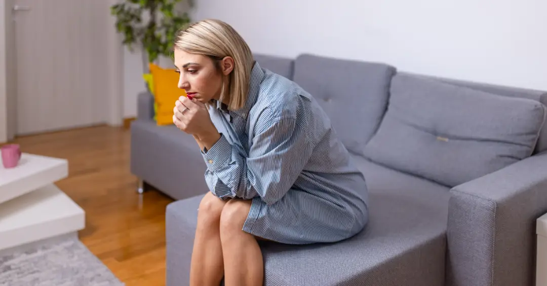 Woman on sofa leaning forward in an "overthinking" pose.