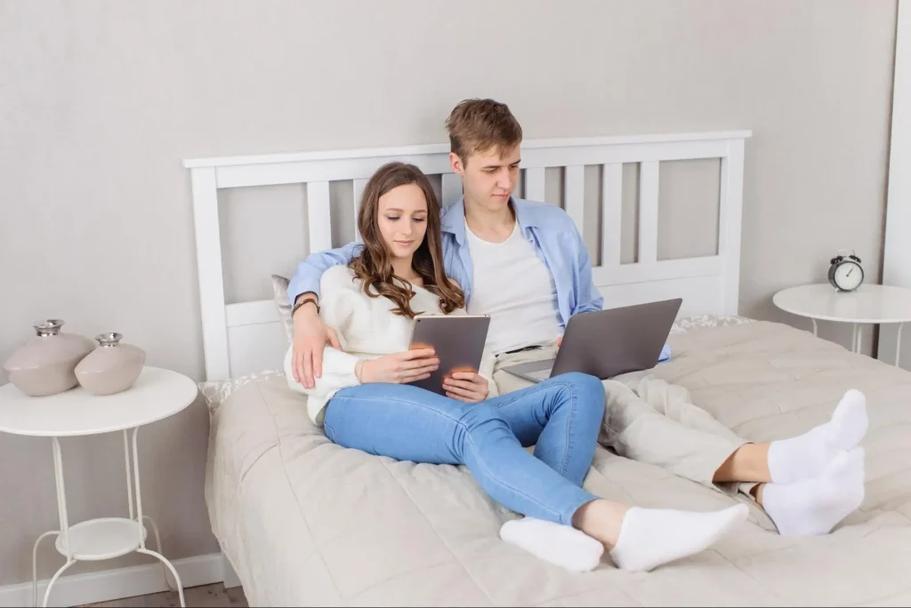 A smiling couple working through issues and reaching breakthrough while on a video call with their online relationship counselor as they realize that an apology without change is manipulation.