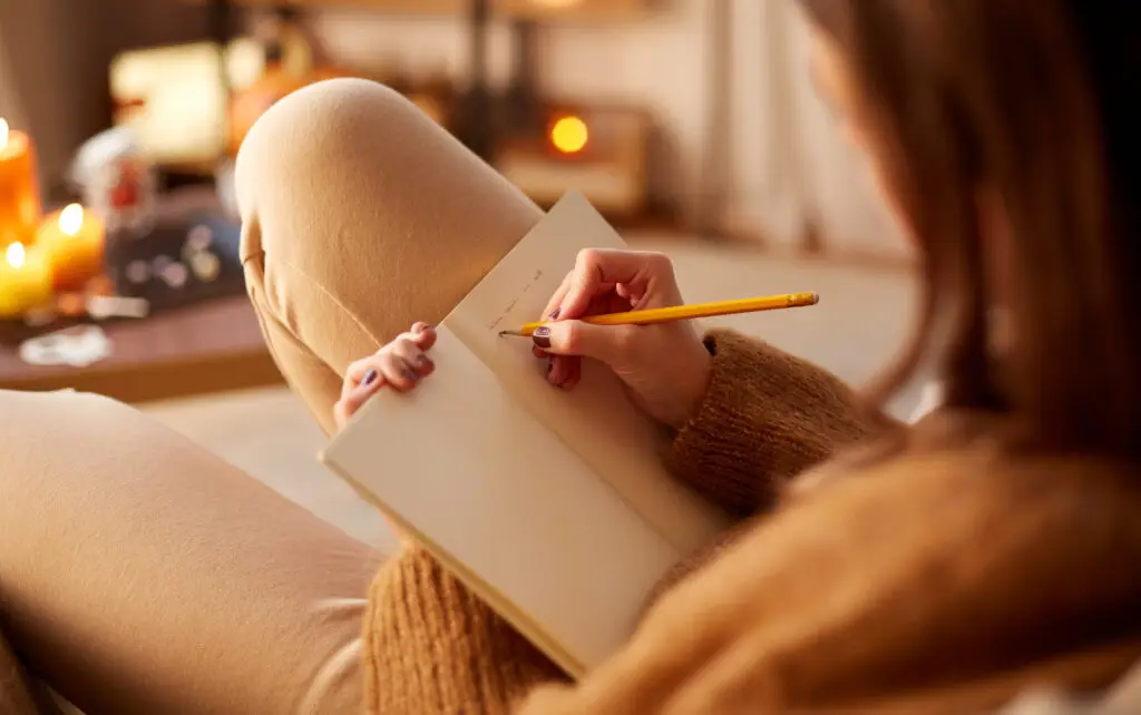 10 Effective Ideas On How To Stop Overanalyzing And Calm Your Anxious Mind A woman is seen writing in a journal as a way to process thoughts that might usually be overanalyzed.