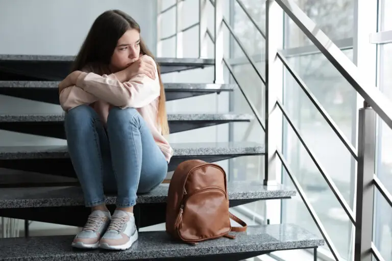Young girl sitting on steps with her backpack, struggling with both ADHD and social anxiety.