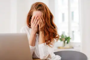 This photo shows a woman holding her head in her hands looking emotionally distraught, representing what it can feel like to be struggling with post partum rage.