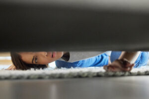 ADHD object permanence causes you to forget where you put things. This woman is looking for something under a couch.
