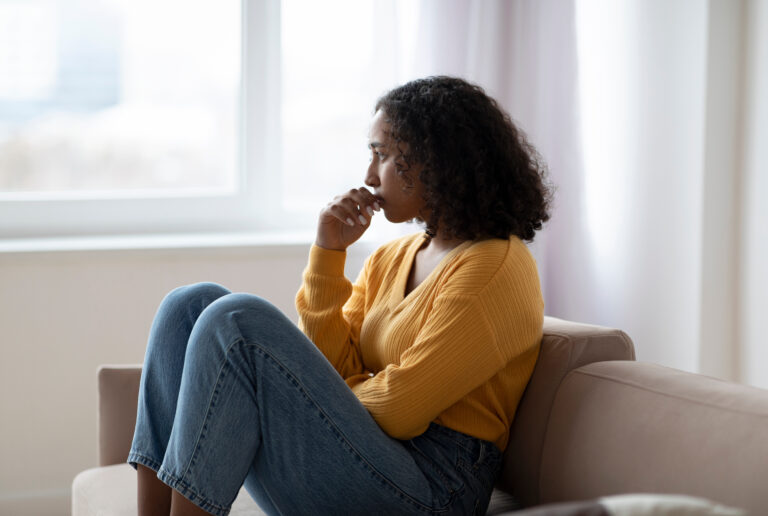 How Narrative Exposure Therapy Helps You Overcome PTSD and Break Free From Generational Trauma Image of a woman looking pensively out a window, struggling with PTSD.
