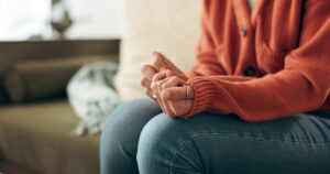 Image of a woman fussing with the sleeve of her sweater on a couch, in the middle of Narrative Exposure Therapy.