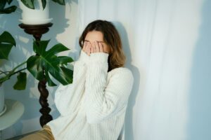 Woman holding her hands to her face after letting out a Freudian slip.