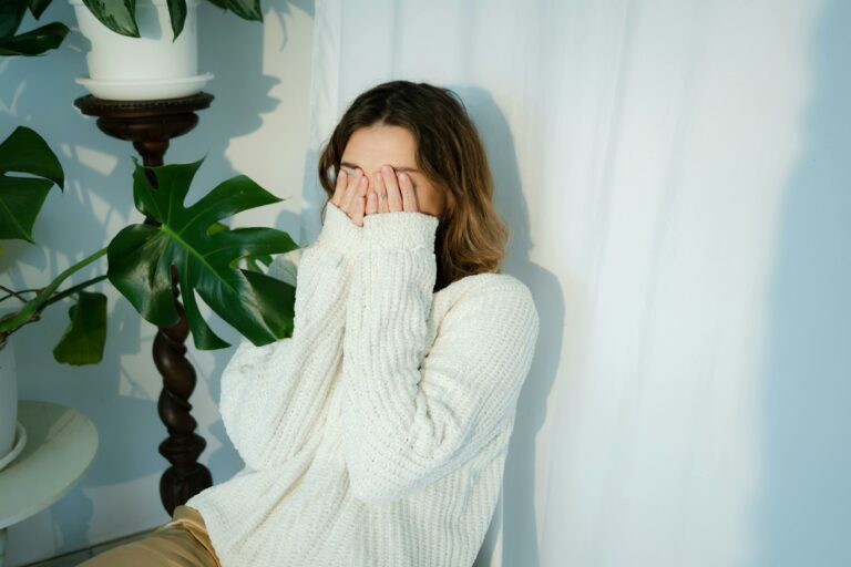 Woman holding her hands to her face after letting out a Freudian slip.
