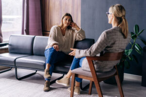 Two women chatting in a room discussing when to see a psychotherapist vs psychiatrist.