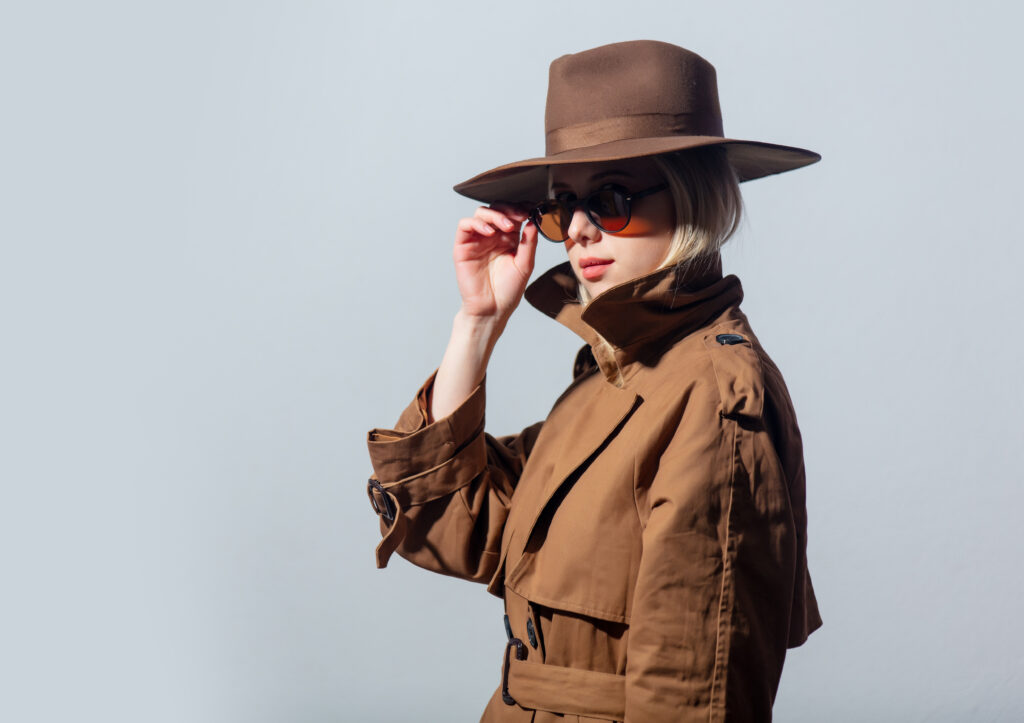 Woman in a trench coat, sunglasses, and a fedora hat to show how it can be difficult to recognize a covert narcissist.