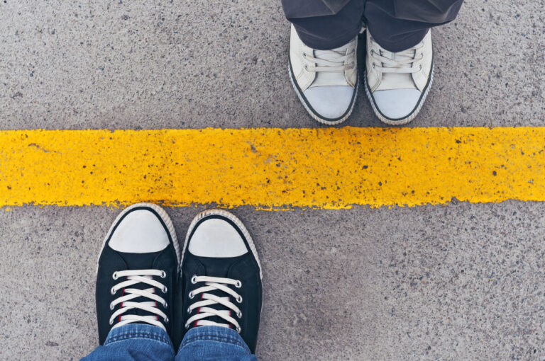 Sneakers on either side of a yellow line to represent boundaries for people on the asexuality spectrum.
