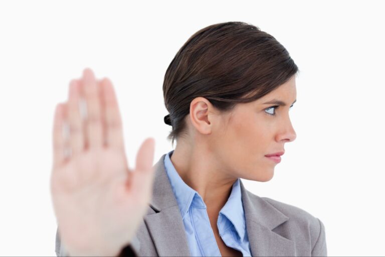 A woman looking dismissive because she is holding her hand up and looking away.