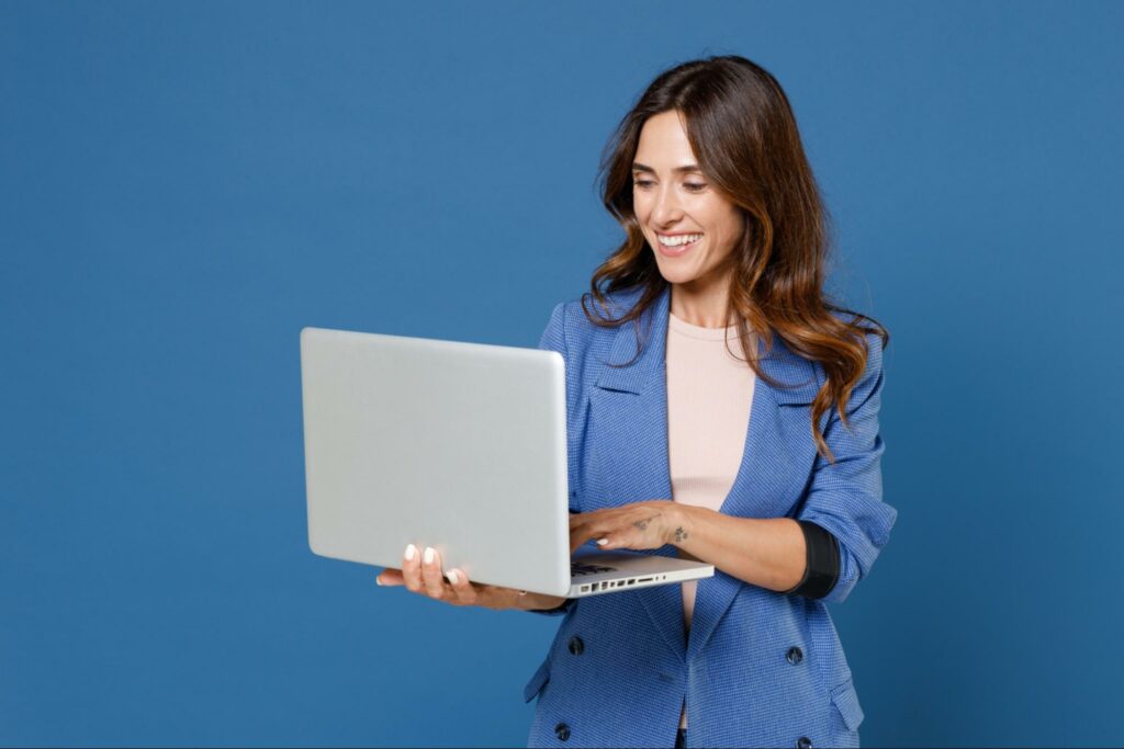 A woman excited to learn how to become less emotionally unavailable through online therapy on her laptop.