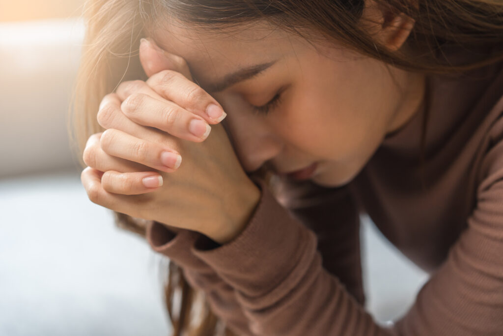 Young woman praying and asking God, 'Why do I hate myself so much?'
