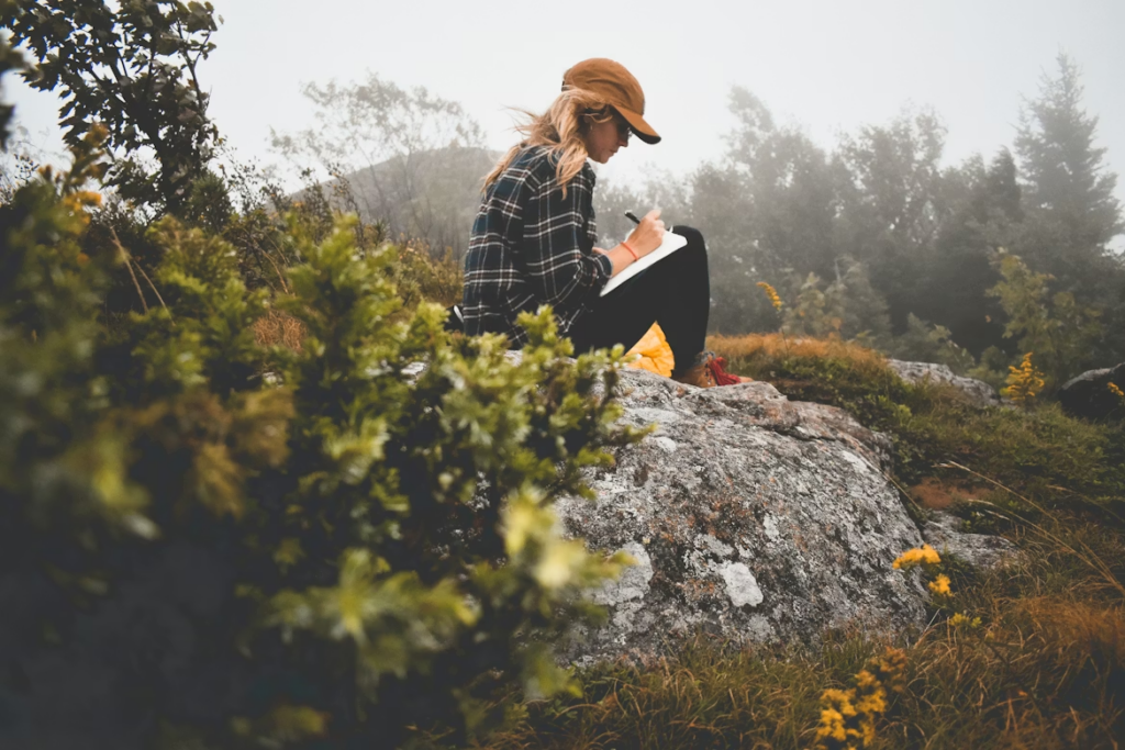 Woman working on her identity formation by journaling out her internal narrative in nature.