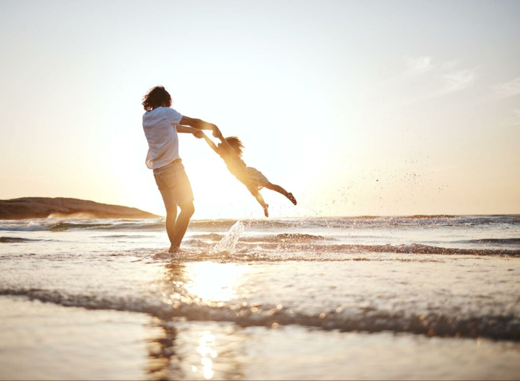 Father and daughter on a beach experiencing identity exploration through shared family experiences.
