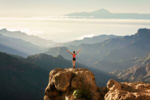 Woman feeling alive and in alignment with her identities and identity formation on a mountaintop in the morning.