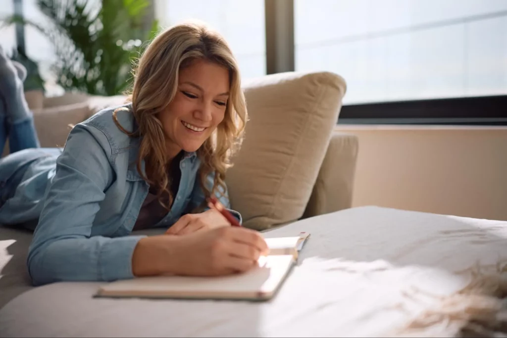A woman writing down good things that happened today to build her self esteem.