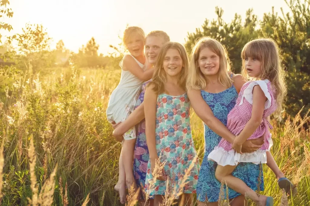 Five sisters smiling in a field, representing the joy and pain of having many siblings, and the family issues that can come from that dynamic.