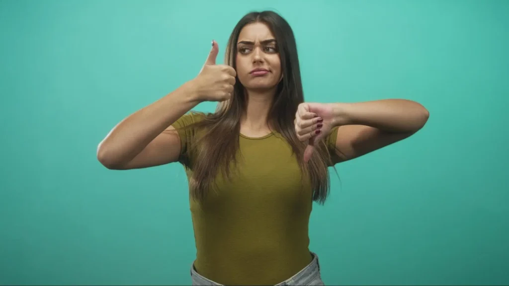 A woman giving a thumbs-up and a thumbs-down is an example of giving mixed signals.