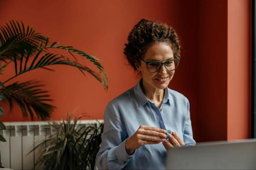 An older female co-worker fidgeting with a spinner toy to help her focus during a virtual meeting.
