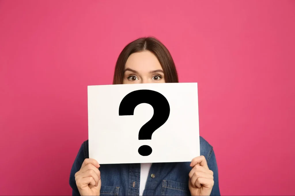 A woman showing a white paper with a black question mark on the front, representing the question, “What is stimming ADHD?”