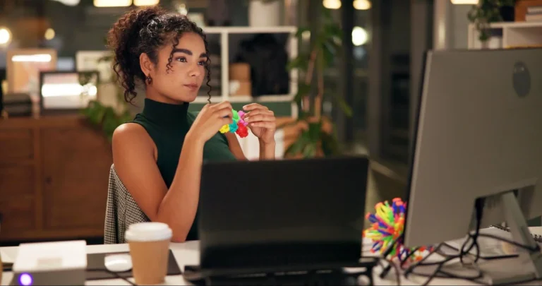 Makin Wellness Articles A female office worker playing with a fidget toy while reviewing her work.