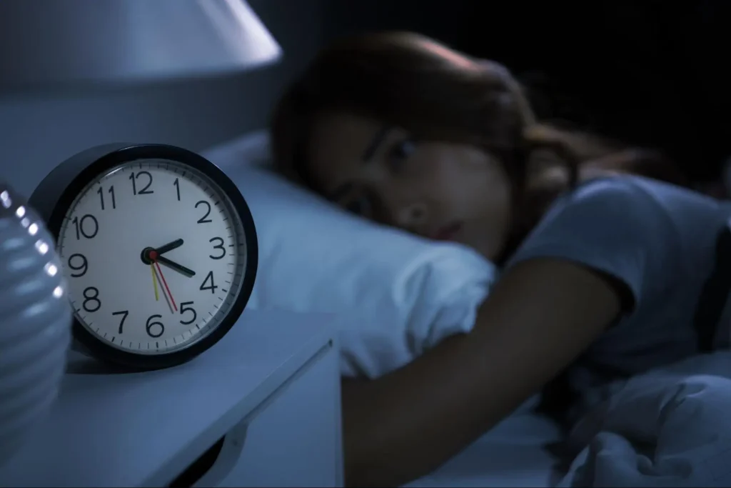 Young woman lying in bed with ADHD and sleep disorders, unable to fall asleep.