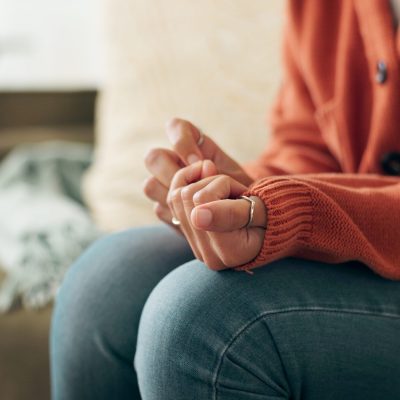 Image of a woman fussing with the sleeve of her sweater on a couch, in the middle of Narrative Exposure Therapy.