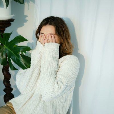 Woman holding her hands to her face after letting out a Freudian slip.