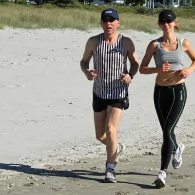 man and woman running on beach