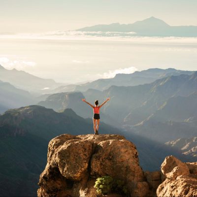 Woman feeling alive and in alignment with her identities and identity formation on a mountaintop in the morning.
