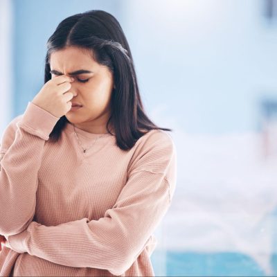 Young woman holding her face in distress, experiencing intense self-criticism, self-hatred, and depression.
