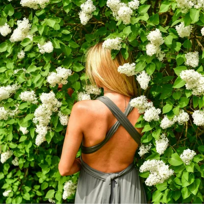 A woman standing near a hedge made of lilac bushes considers how setting healthy boundaries in her relationships is akin to a living fence.