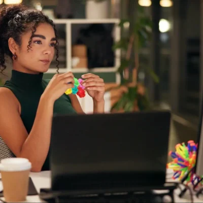 A female office worker playing with a fidget toy while reviewing her work.