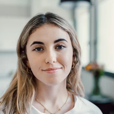 A young blonde woman looking at the camera in peace, smiling because she learned how to control her emotions.